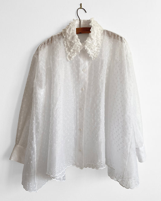 White lace blouse on a hanger against a white background