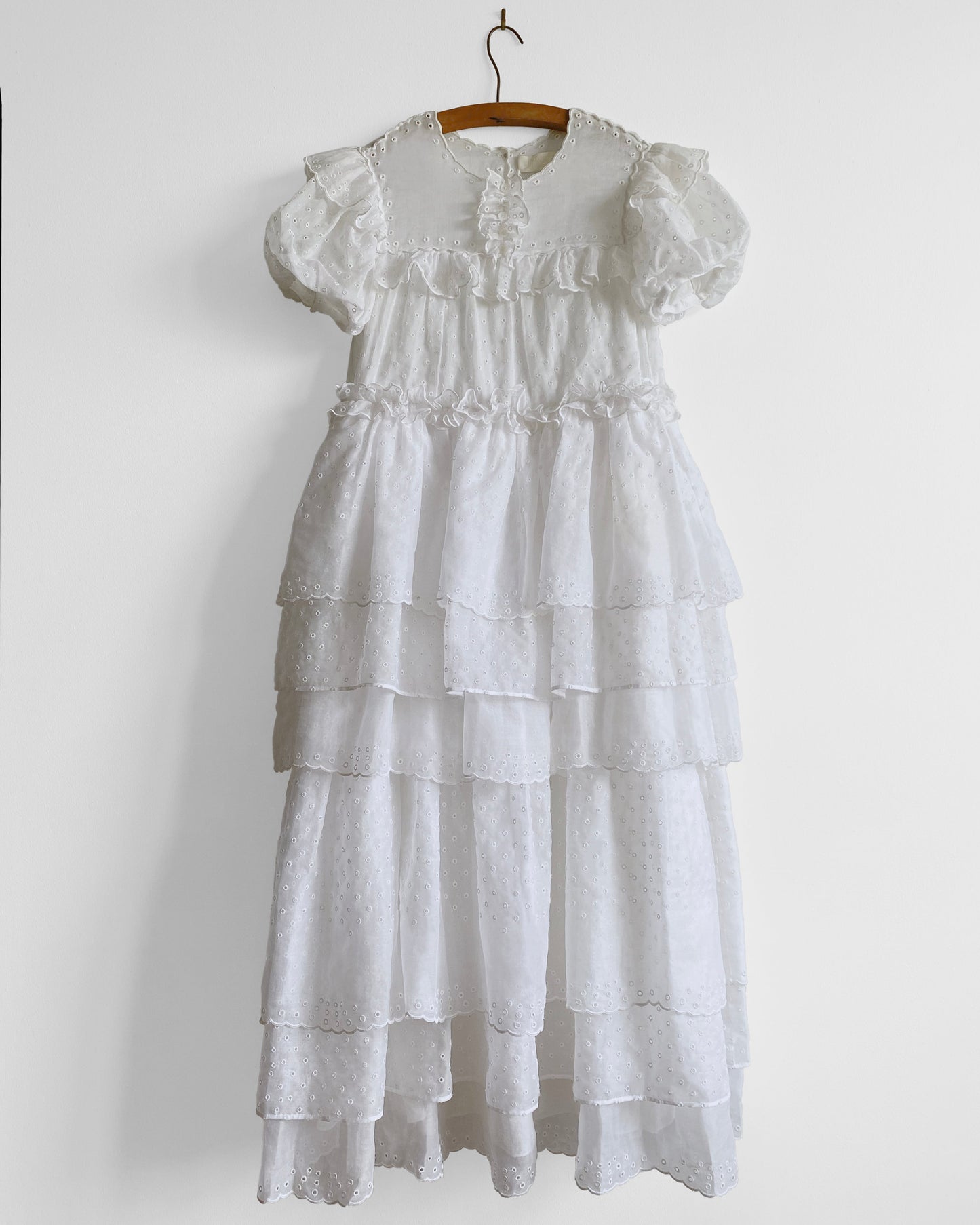 White tiered dress on a hanger against a white background