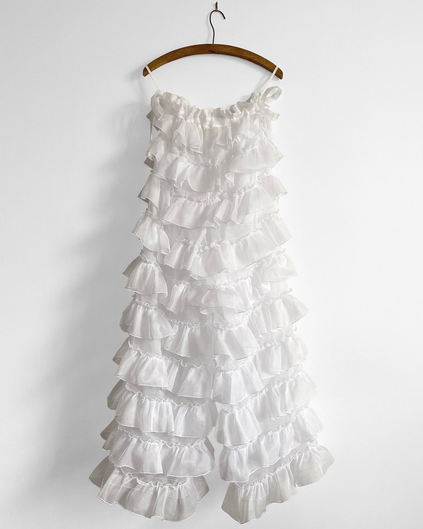 White ruffled dress on a hanger against a white background