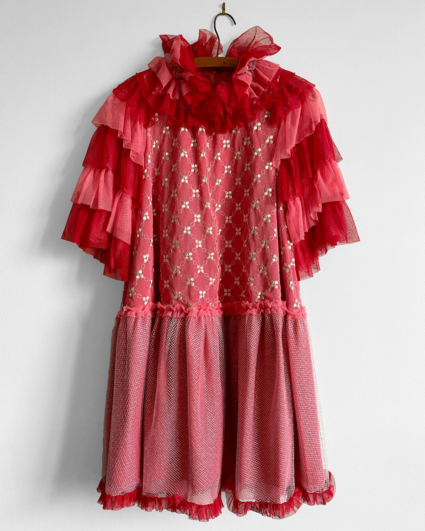 Red ruffled dress on a hanger against a white background
