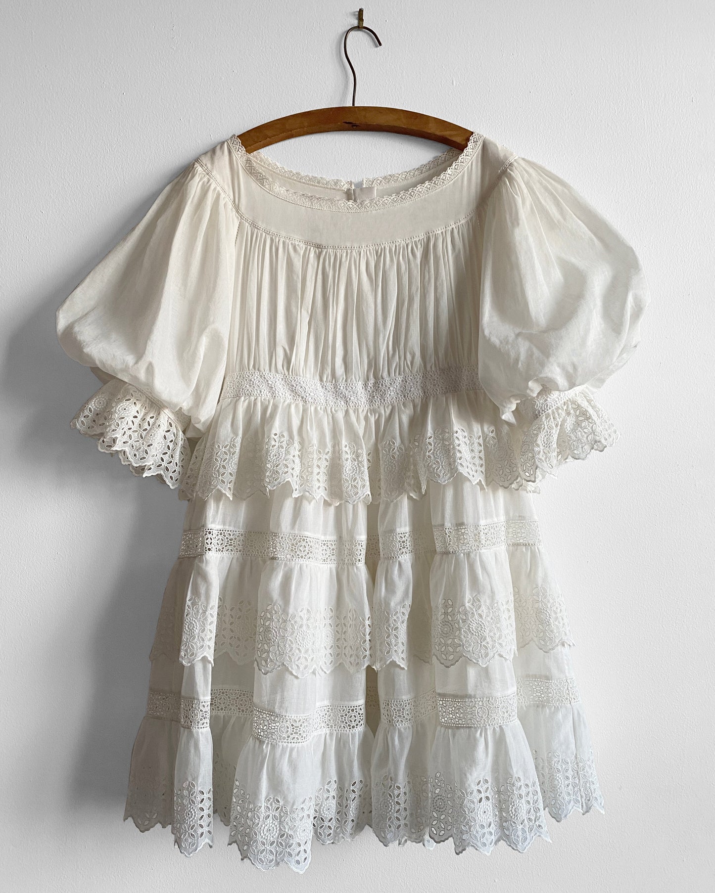 White lace dress on a wooden hanger against a white background