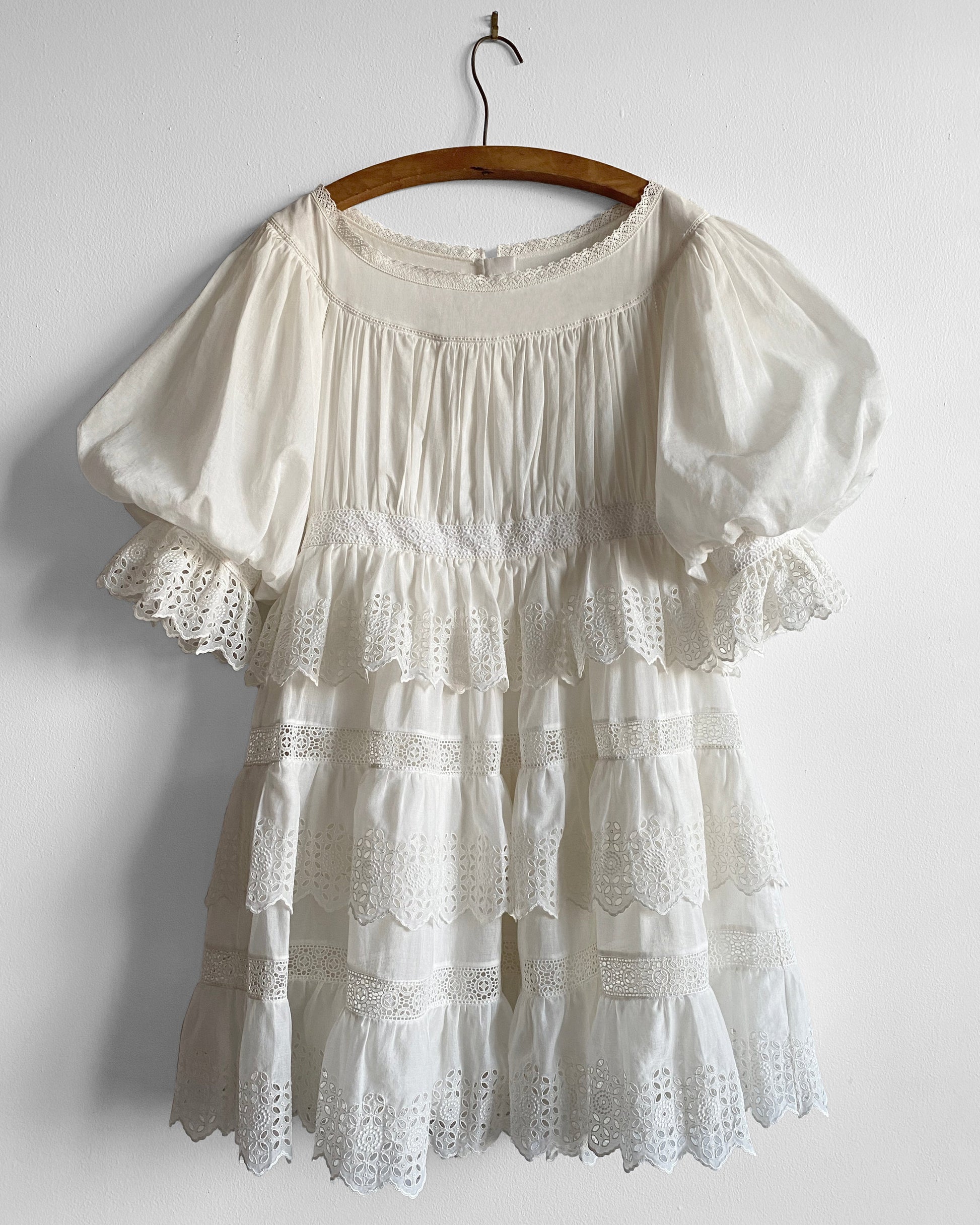 White lace dress on a wooden hanger against a white background