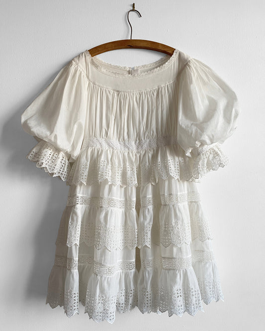 White lace dress on a wooden hanger against a white background